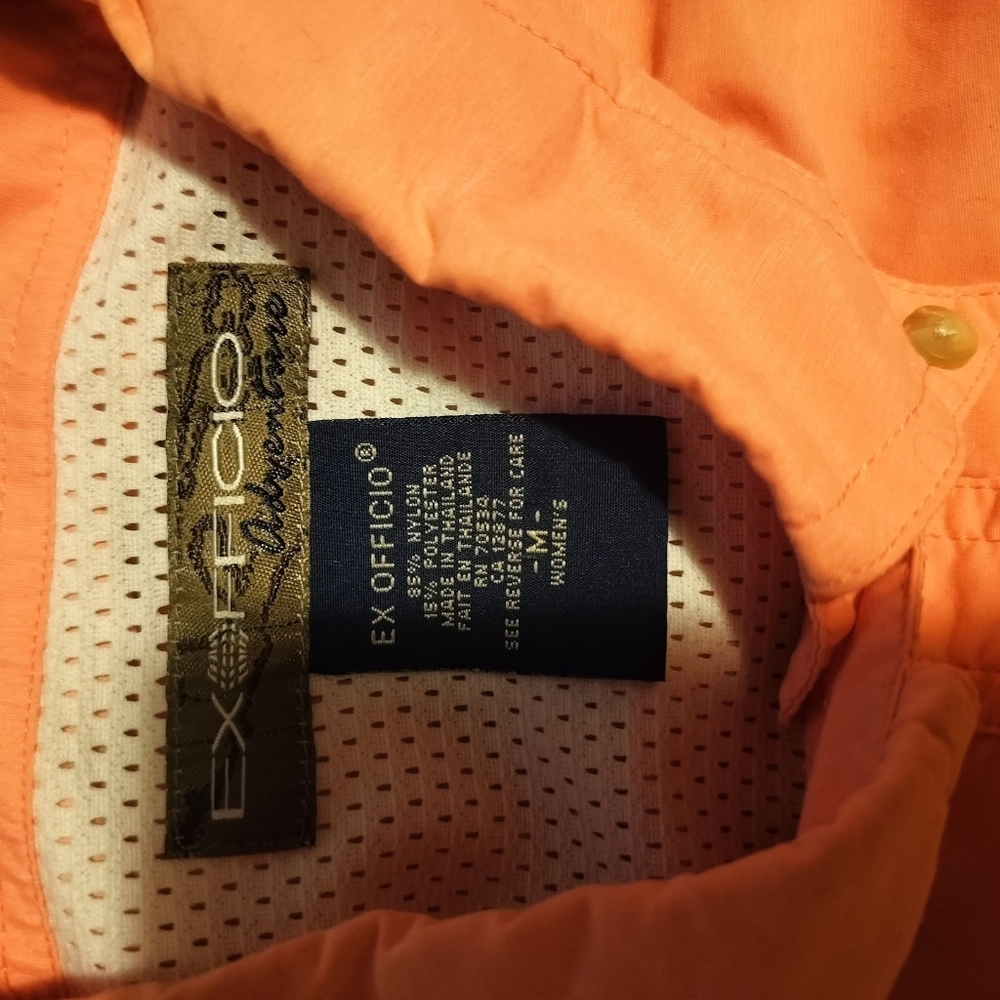 Two ExOfficio Long Sleeve Button Up Shirts One Orange And The Other Cream.